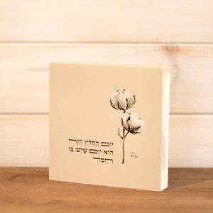 בלוק עץ ריבוע סגנון נקי בוטני כפרי עם איור כותנה והכיתוב יום החולין הזה הוא יום שיש בו חסד של רחל שפירא שמנת על מדף או לתליה