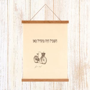 הדפסה ייחודית על בד קנבס בין מוטות עץ כפריים לתלייה על קיר באווירה כפרית וטבעית עם מילות השיר של אהוד בנאי השביל הזה מתחיל כאן איור עדין רישום אופניים