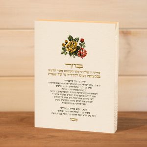 ברכת הדלקת נרות שבת מודפסת על בלוק עץ מלבן עומד סגנון דמוי רקמה אדום ירוק צהוב טיפוגרפי עיצוב נקי מינימליסטי להנחה על המדף לצד הנרות