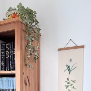 הדפסה ייחודית על בד קנבס בין מוטות עץ כפריים לתלייה על קיר באווירה כפרית וטבעית בפורמט צר ואורך מתאים לתליה על קיר צר במעברים עיצוב מיוחד עם המילים ניצנים נראו בארץ שיר השירים איורים בוטנים פרחים ירוק ורוד טורקיז חרדל