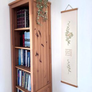 הדפסה ייחודית על בד קנבס בין מוטות עץ כפריים לתלייה על קיר באווירה כפרית וטבעית בפורמט צר ואורך מתאים לתליה על קיר צר במעברים עיצוב מיוחד עם המילים ואתה שלום וביתך שלום איור פרחים צמחים ירוק חום וציפור