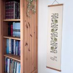 הדפסה ייחודית על בד קנבס בין מוטות עץ כפריים לתלייה על קיר באווירה כפרית וטבעית בפורמט צר ואורך מתאים לתליה על קיר צר במעברים עיצוב מיוחד עם המילים אך טוב וחסד מתנה לחנוכת בית סגנון דמוי רקמה חום ירוק מנטה