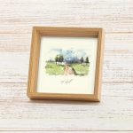 מסגרת תמונה ייחודית ריבוע עומד עם עובי להנחה על מדף עם פרינט של איור כמו צבעי מים עדין של נוף מאיר ושליו גווני ירוק שמנת בהיר עם שביל וברושים תכלת שמים וציפורים עם הכיתוב ללקט אור