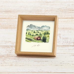 מסגרת תמונה ייחודית ריבוע עומד עם עובי להנחה על מדף עם פרינט של איור כמו צבעי מים עדין של נוף מאיר ושליו גווני ירוק שמנת תכלת חום בהיר עם הכיתוב רגעי נחת