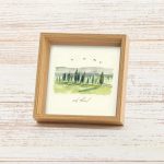 מסגרת תמונה ייחודית ריבוע עומד עם עובי להנחה על מדף עם פרינט של איור כמו צבעי מים עדין של נוף מאיר ושליו גווני ירוק שמנת בהיר עם הכיתוב להוסיף טוב