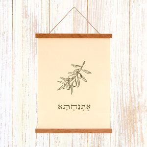 הדפסה ייחודית על בד קנבס בין מוטות עץ כפריים לתלייה על קיר באווירה כפרית וטבעית עם המילה אתנחתא איור ענץ עלים